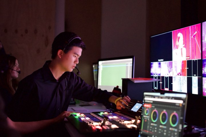 Jun calling a live show from the vision desk, screens glowing pink
