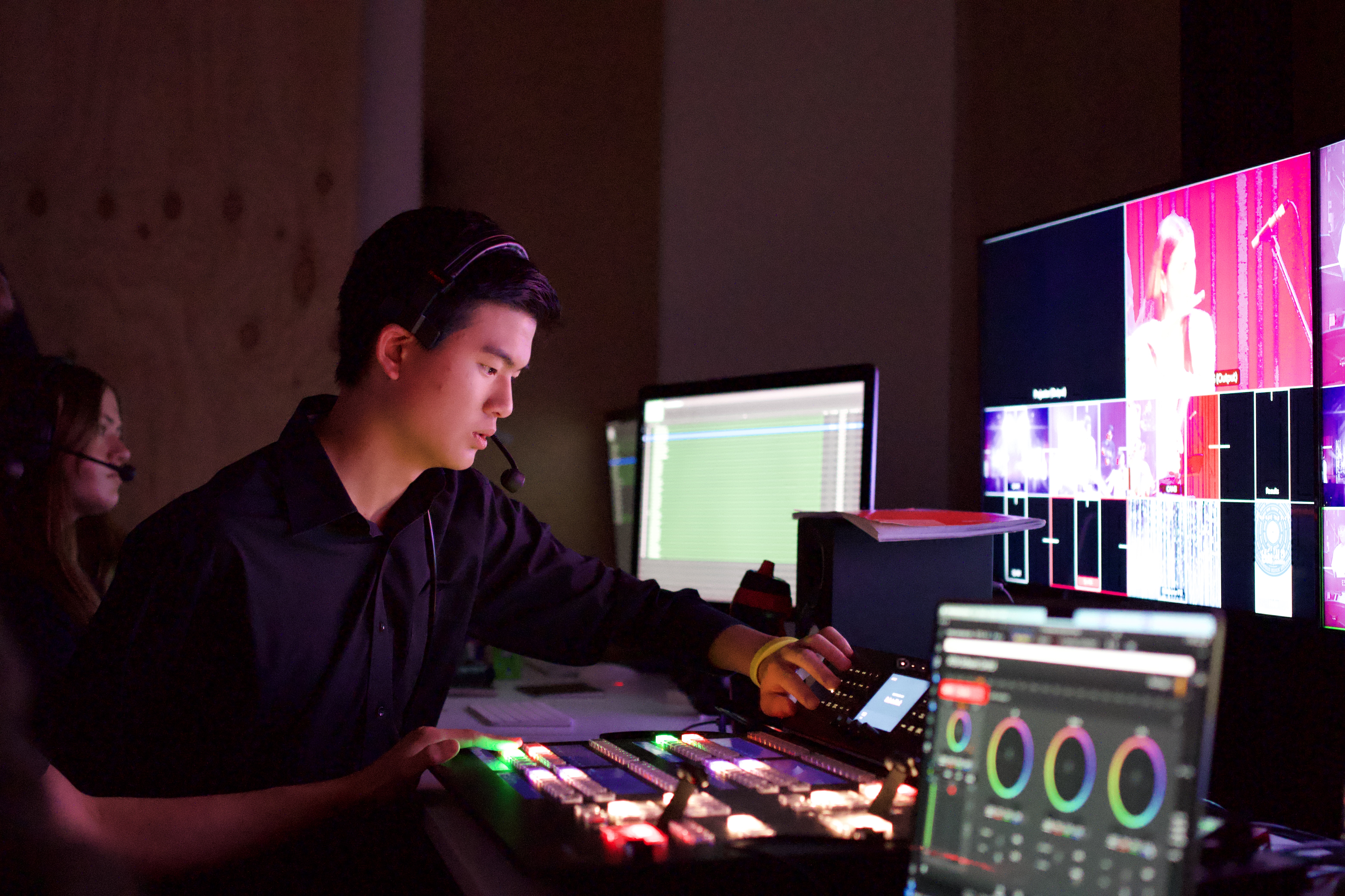 Jun at the vision desk, headset on, screens glowing pink
