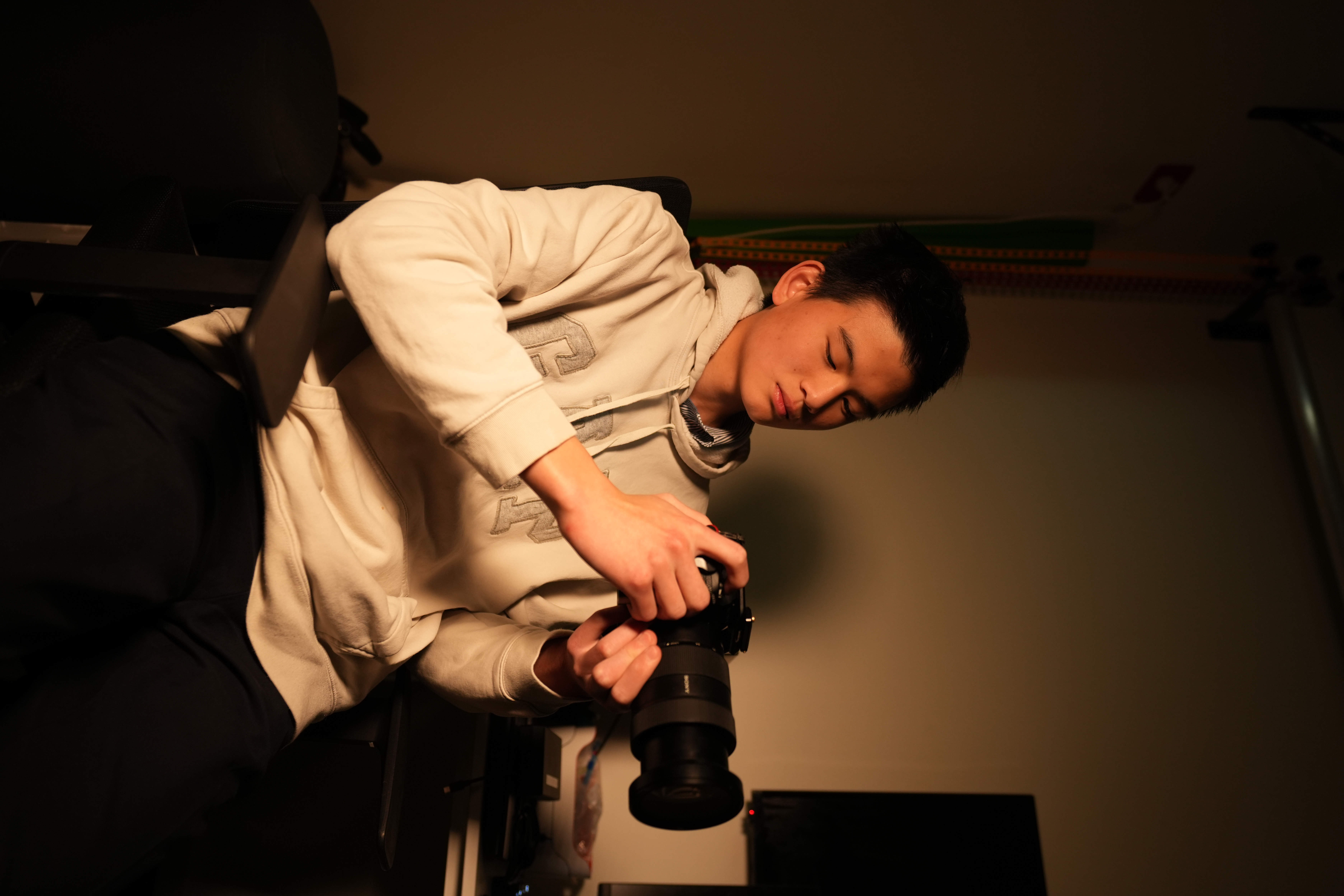 Jun examining a camera in warm amber light