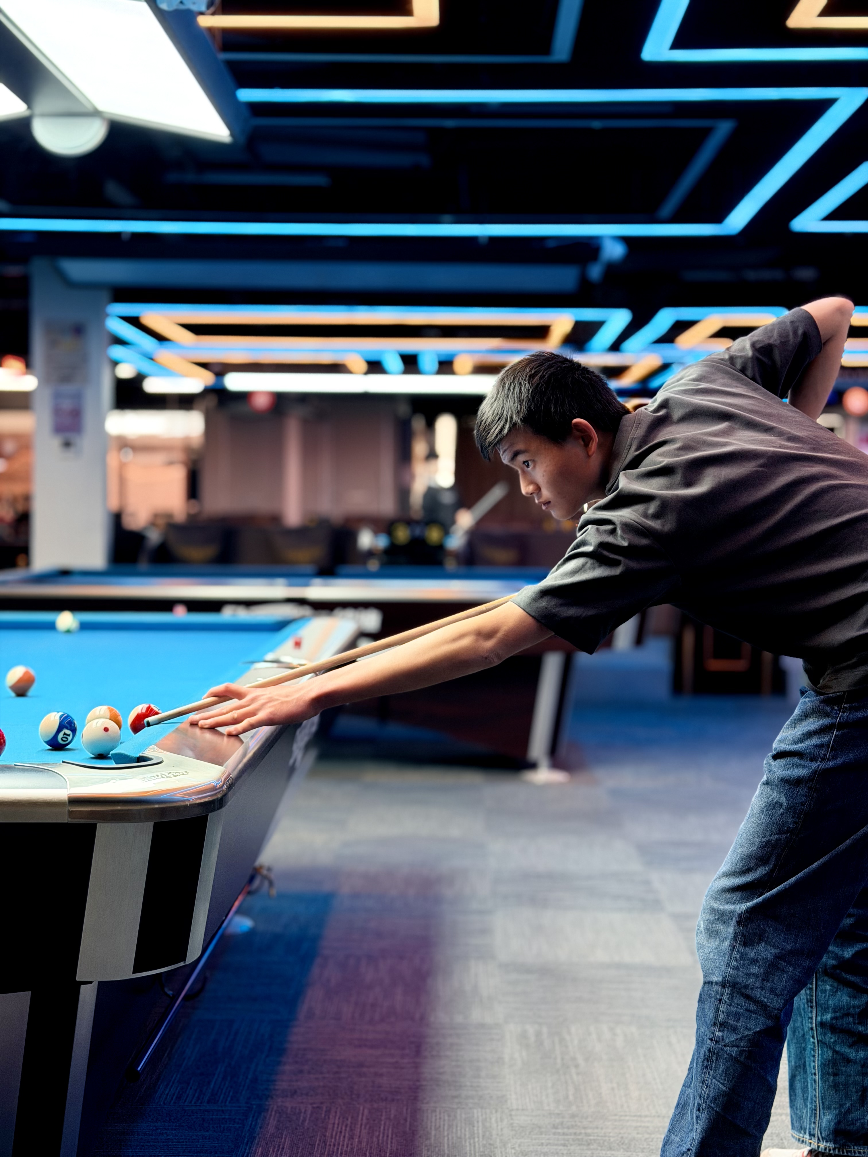Jun leaning over a pool table, focused