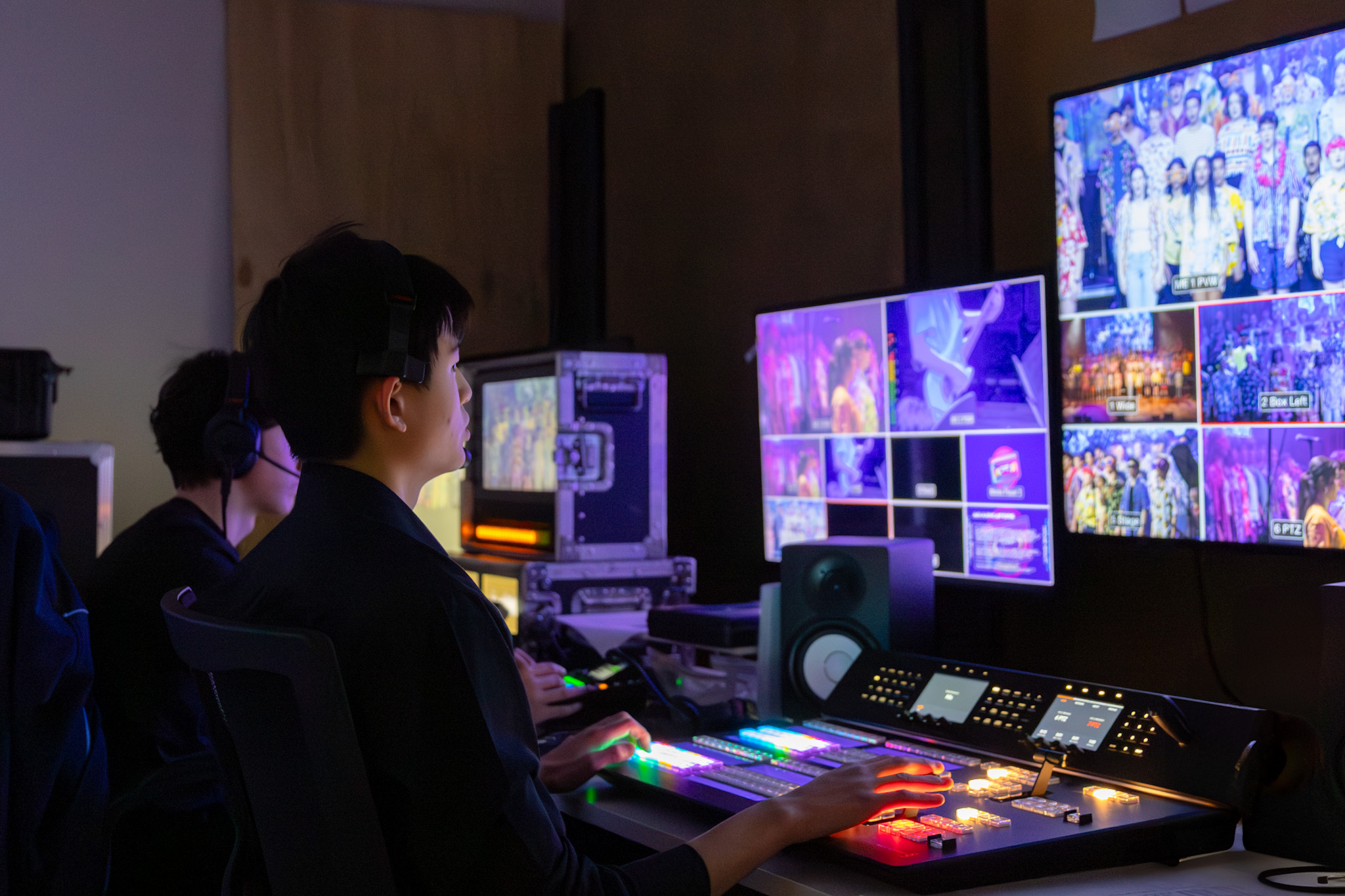Jun at the production desk, monitors filled with live feeds