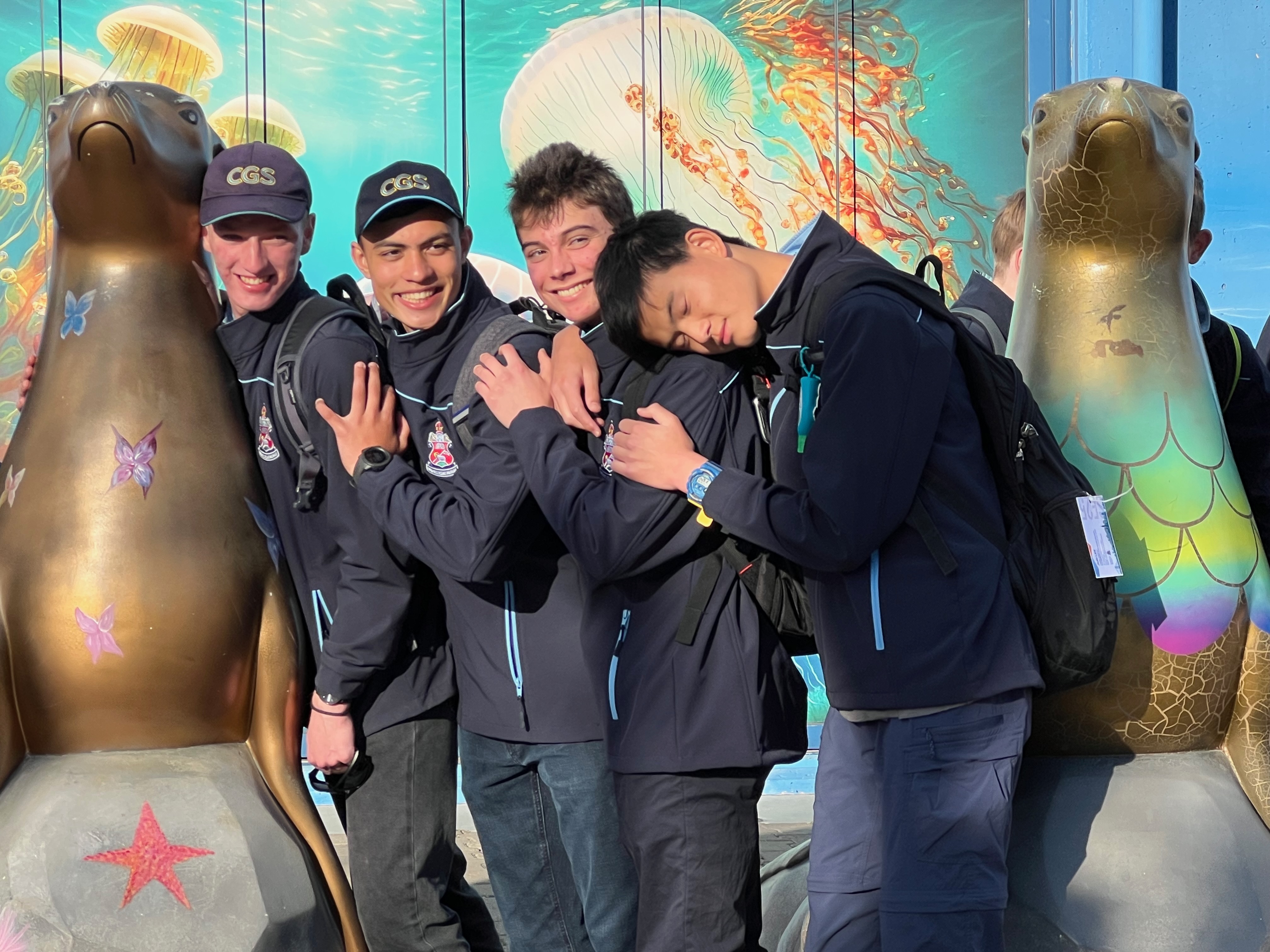 Friends posing with sea lion statues at the aquarium