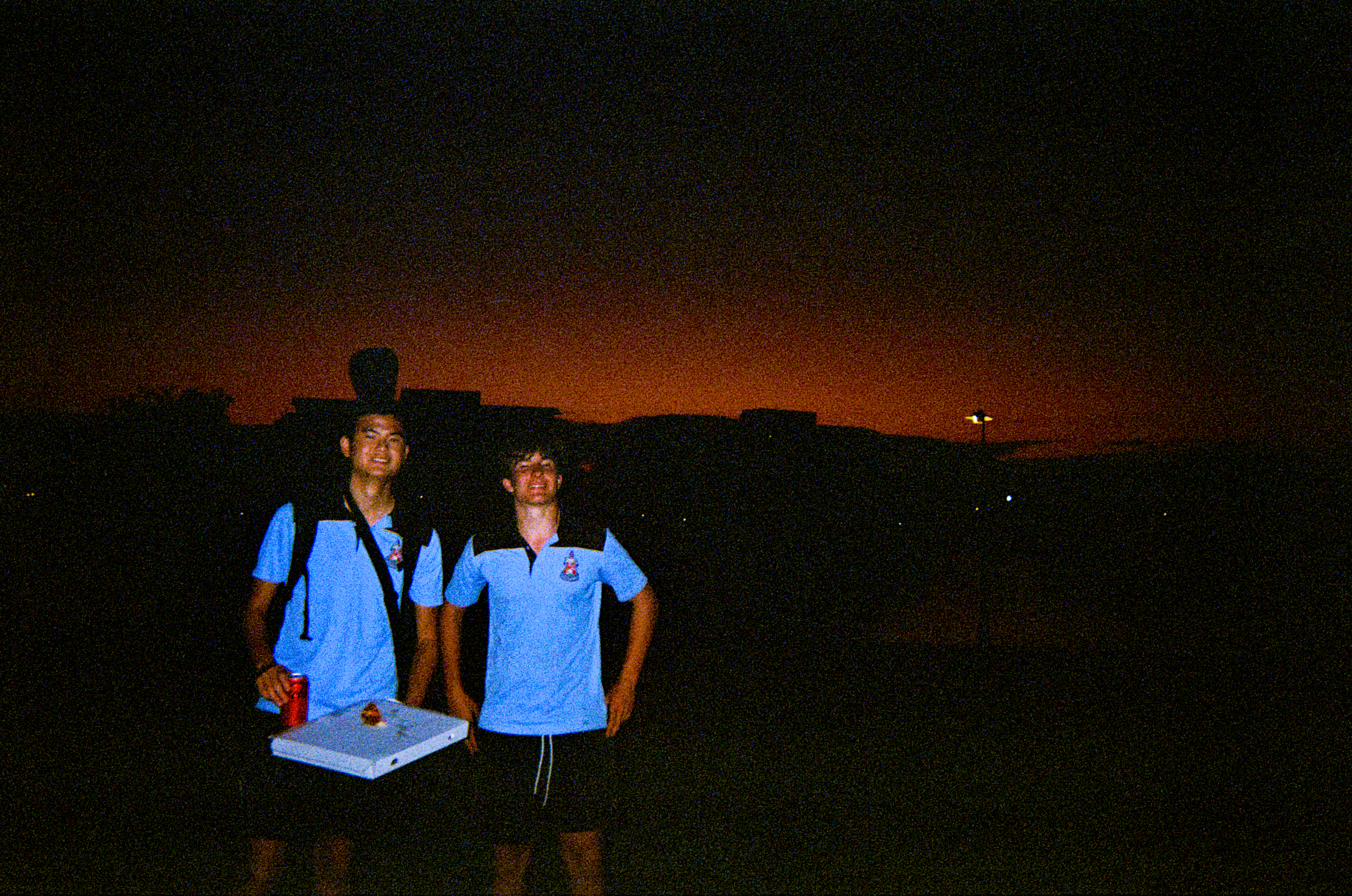 Two guys in team kit at dusk, deep orange sky, on film