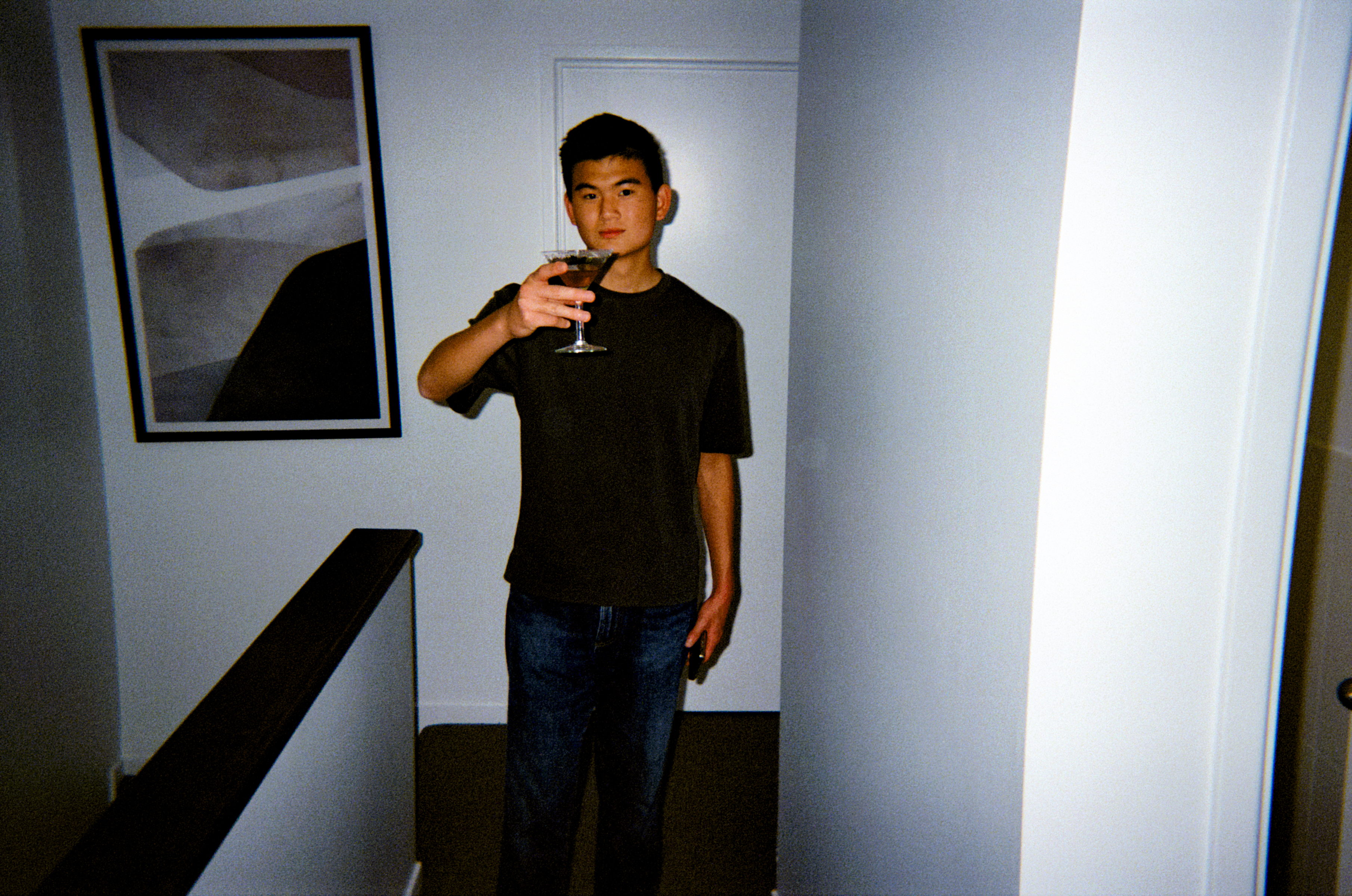 Jun raising a glass in a dark room, on film